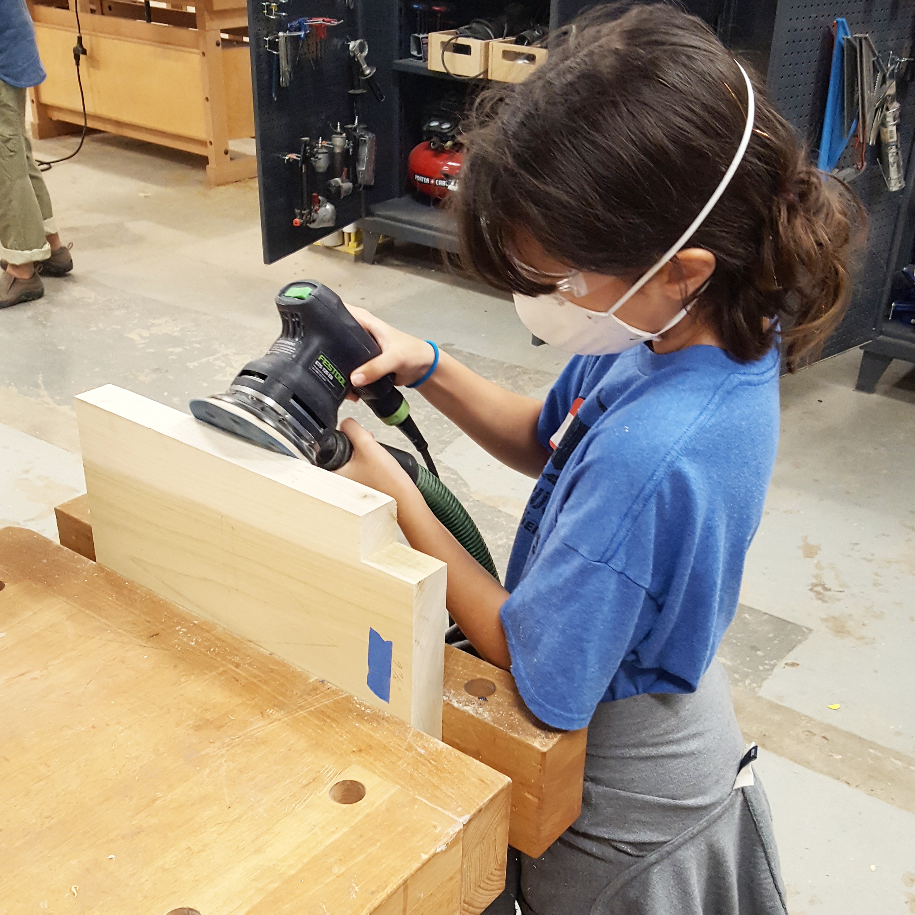 Student sands the leg of their bench
