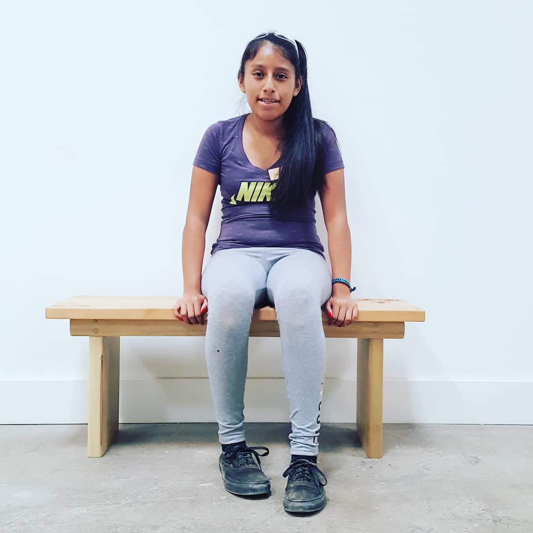 Student sits on the bench they made