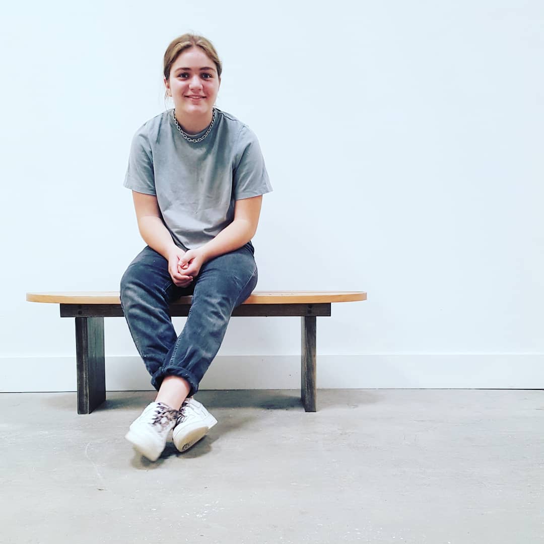 Student sits on the bench they made